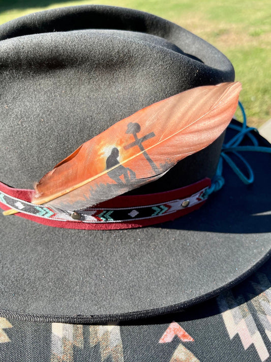 Feather and decorative band on a black hat with a blurred natural background