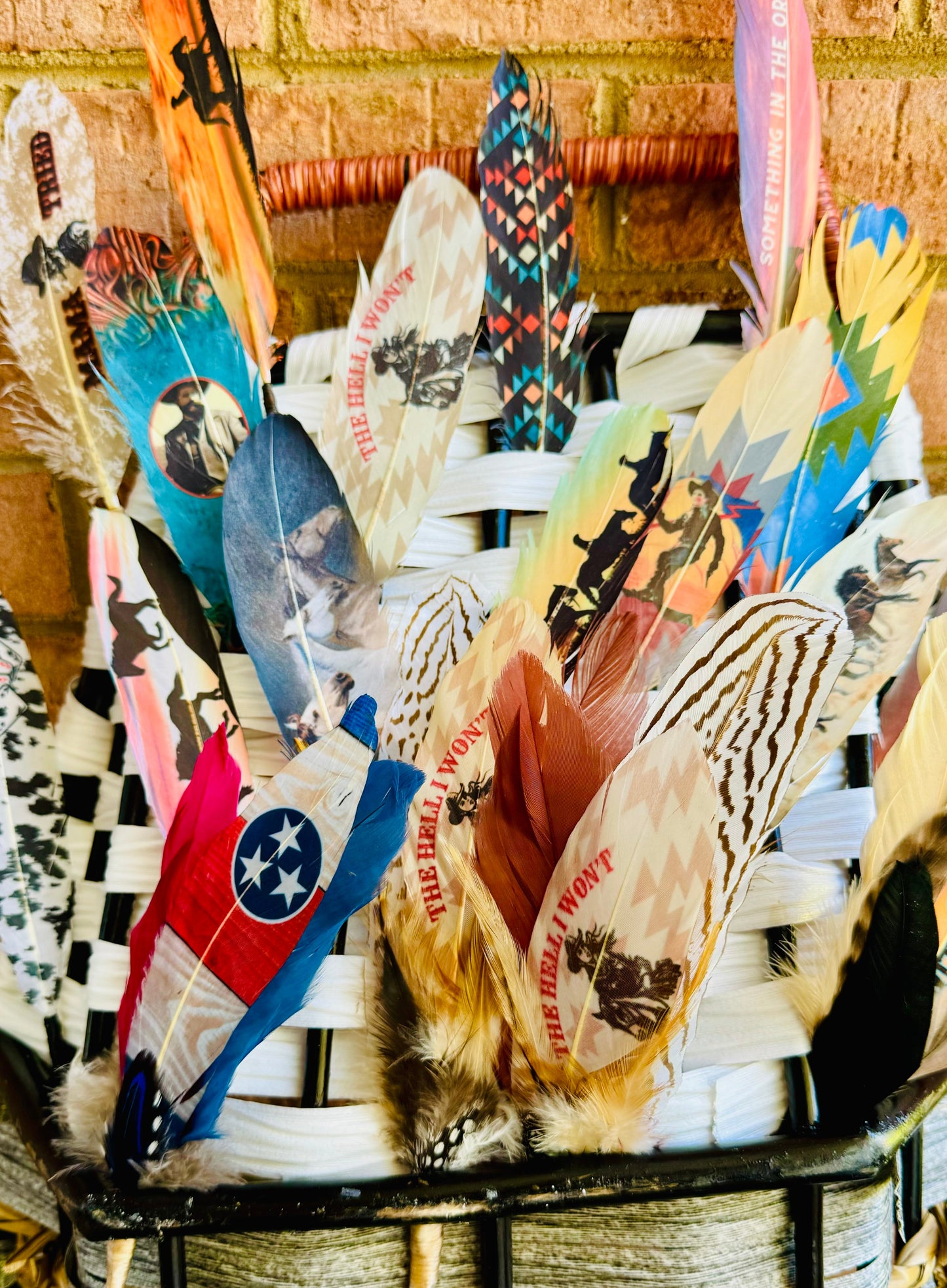 Basket filled with various feathers against a brick wall background