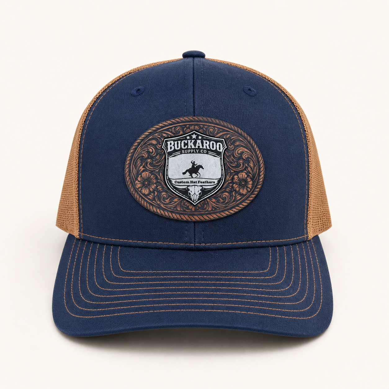 Blue and brown trucker hat with a Buckaroo logo on a white background. Navy and Camel Richardson 112 Western Trucker Hat with Buckaroo Supply Co. logo.