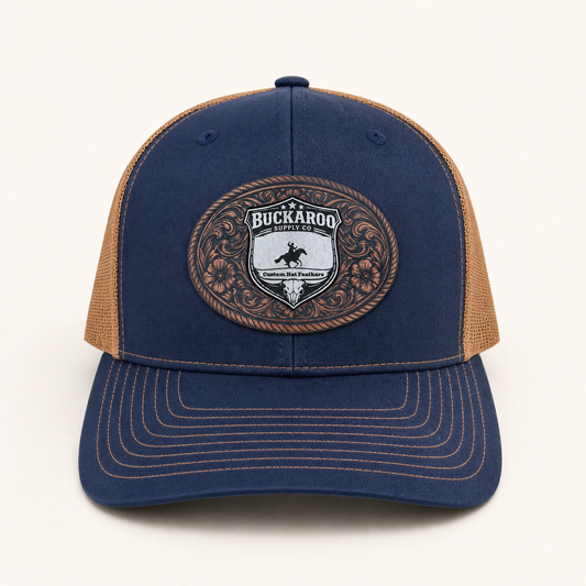 Blue and brown trucker hat with a Buckaroo logo on a white background. Navy and Camel Richardson 112 Western Trucker Hat with Buckaroo Supply Co. logo.