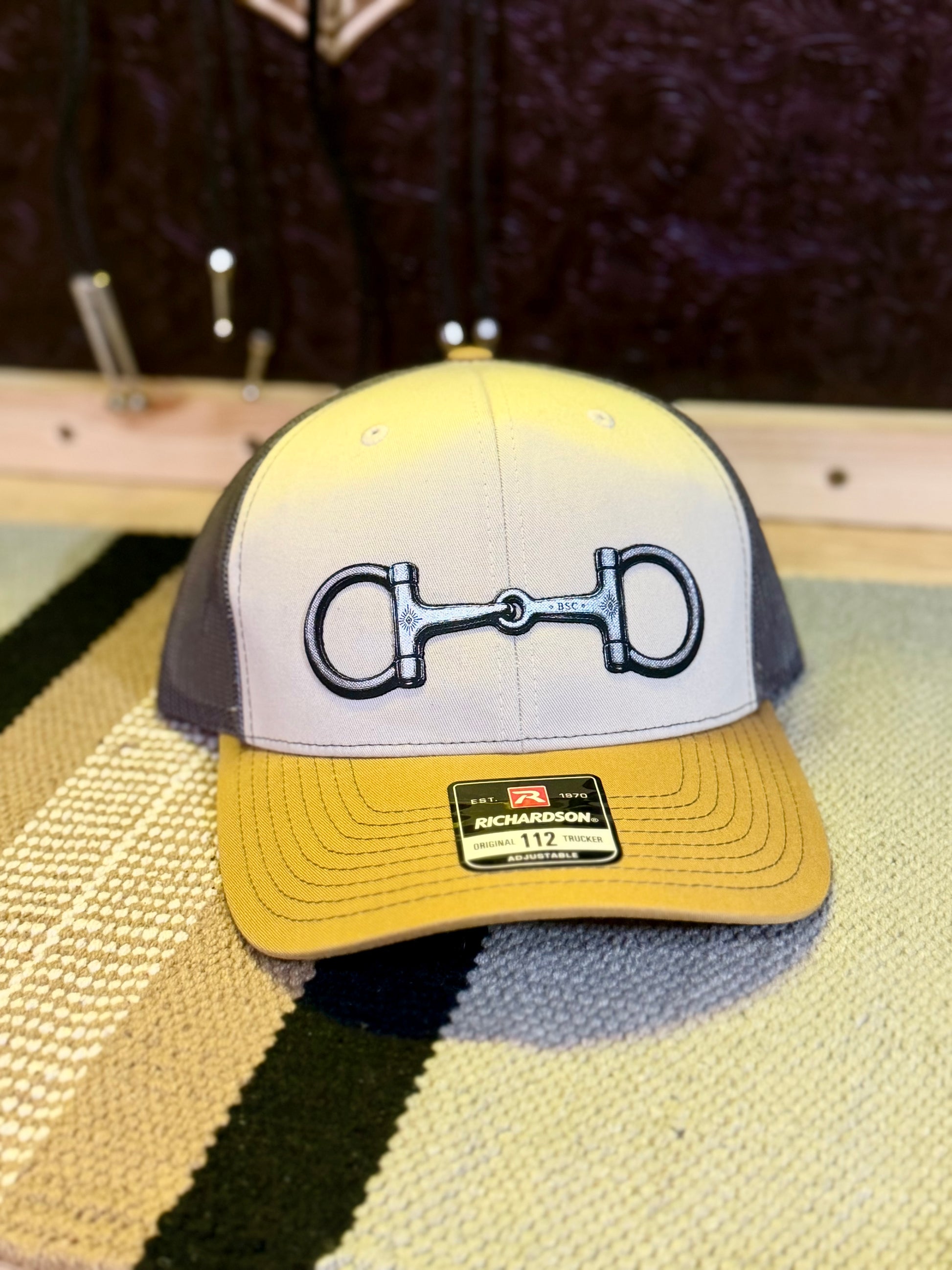 Front view of Richardson 112 trucker hat featuring Buckaroo Supply Co. snaffle bit design