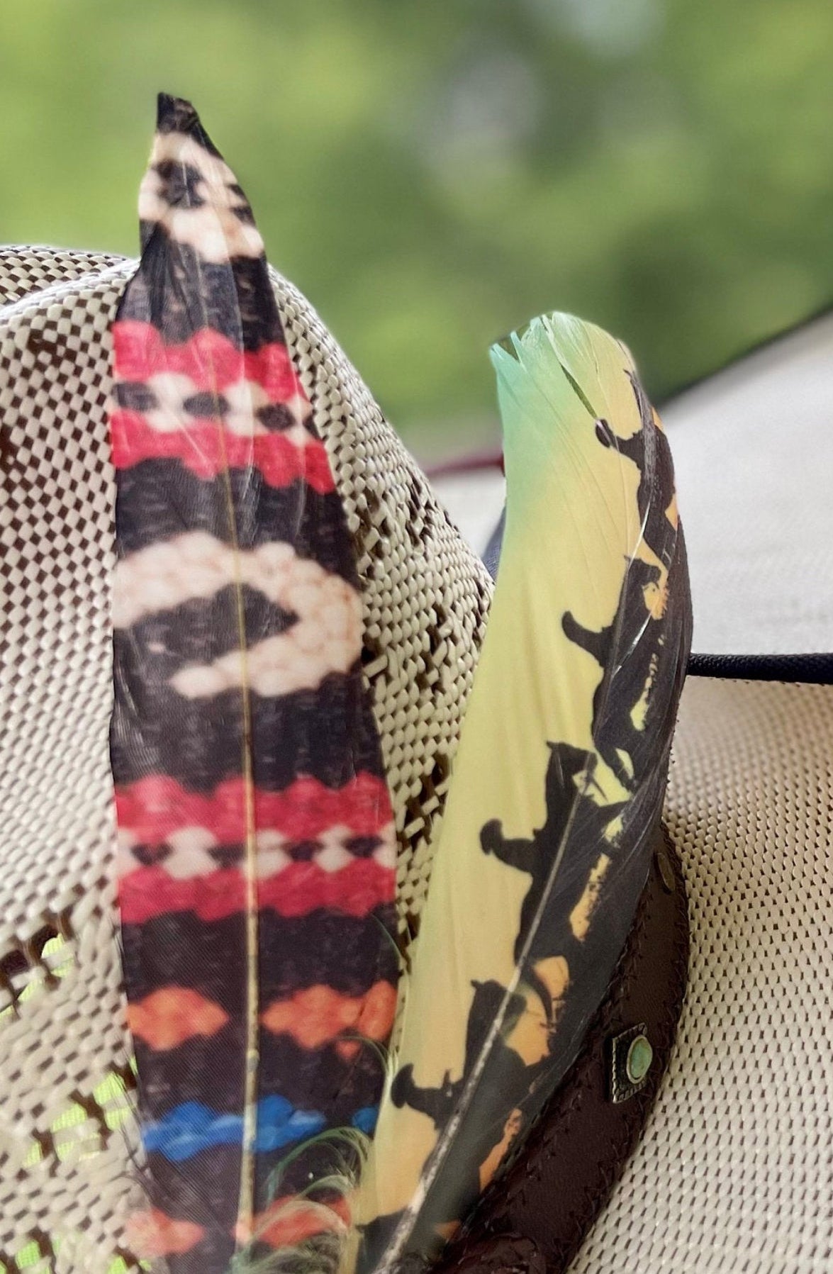 Decorative hat with feathers featuring tribal patterns against a blurred natural background