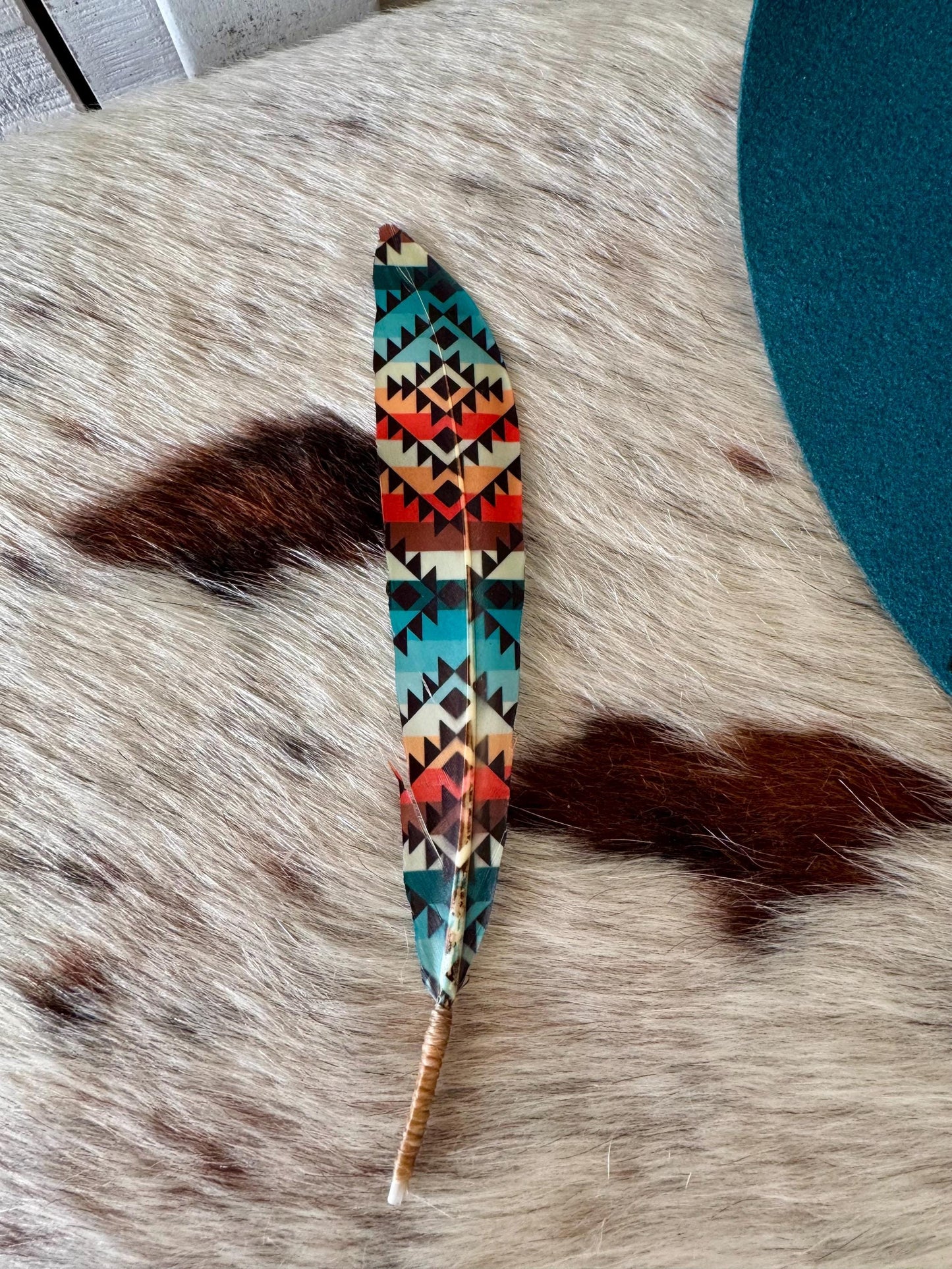 Decorative feather with tribal patterns on a textured surface