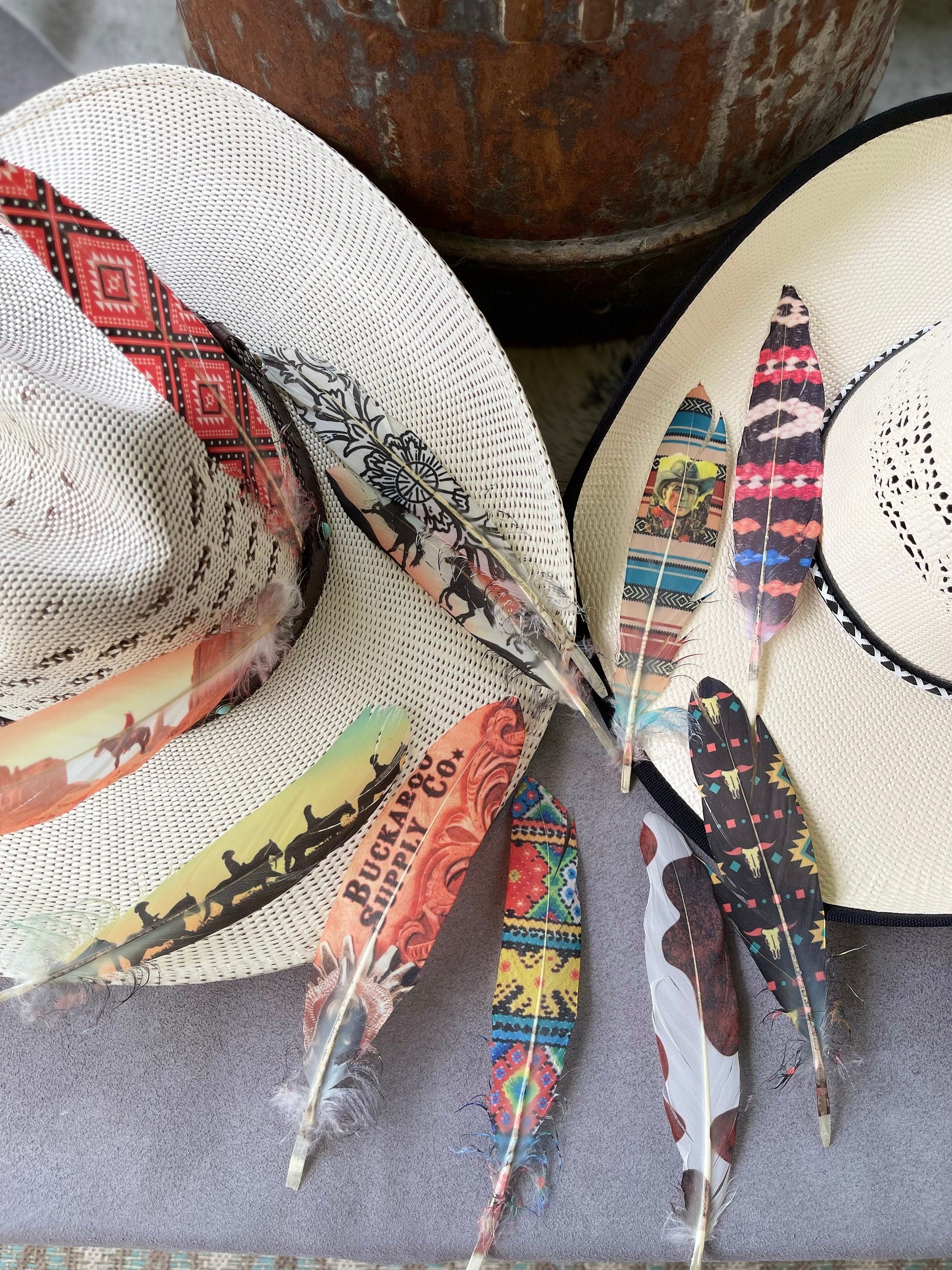 Two hats with decorative feathers on a textured surface