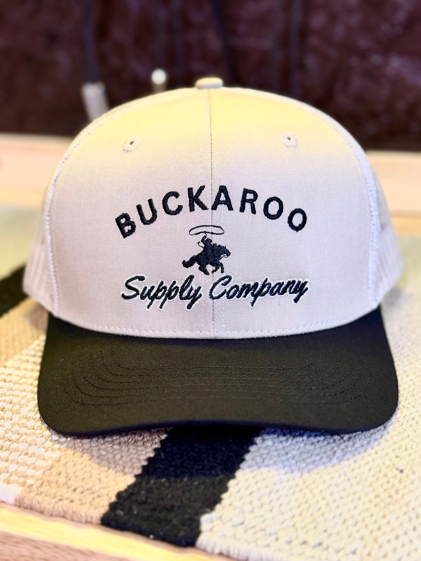 Front view of tan and black Western trucker hat with Buckaroo Supply Company embroidery