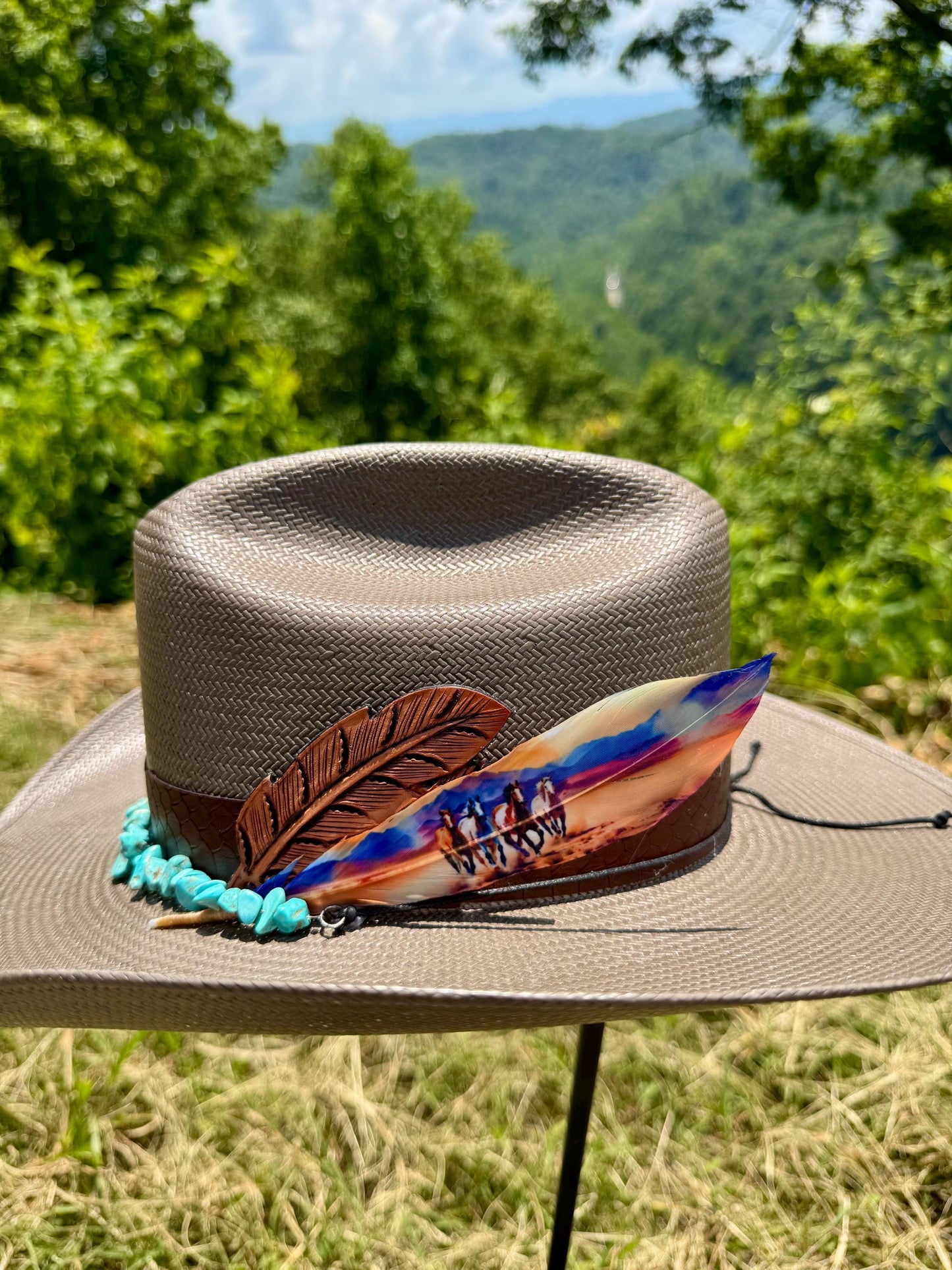 Brown straw hat with decorative feather and beads against a natural background