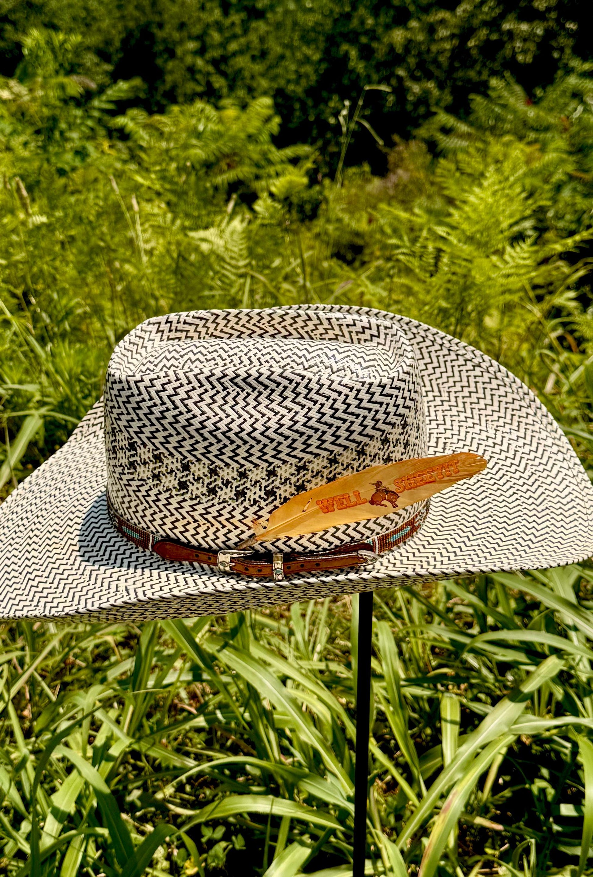 Straw hat with a feather on a stand in a grassy outdoor setting