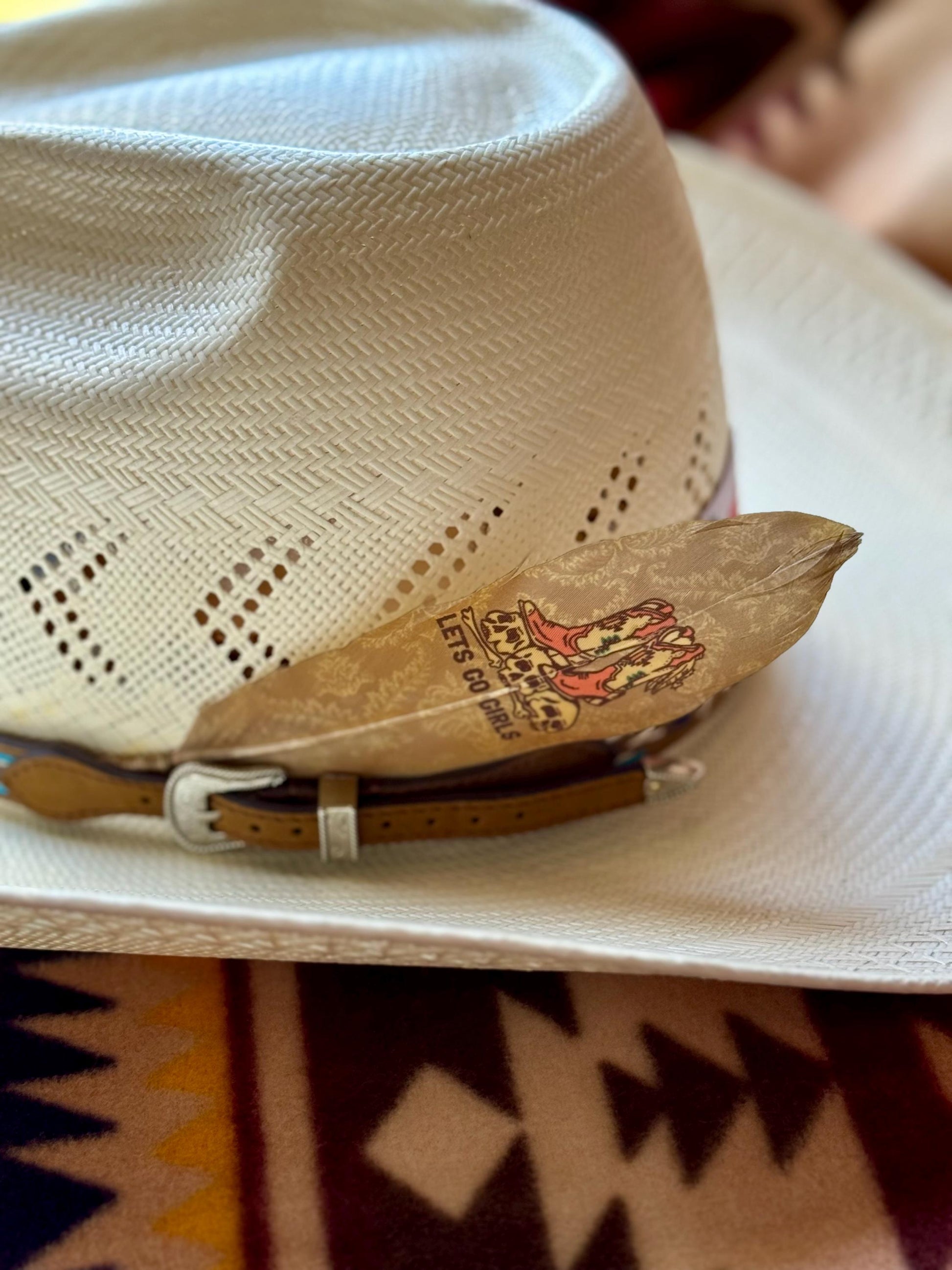 Beige cowboy hat with a brand logo on a patterned surface