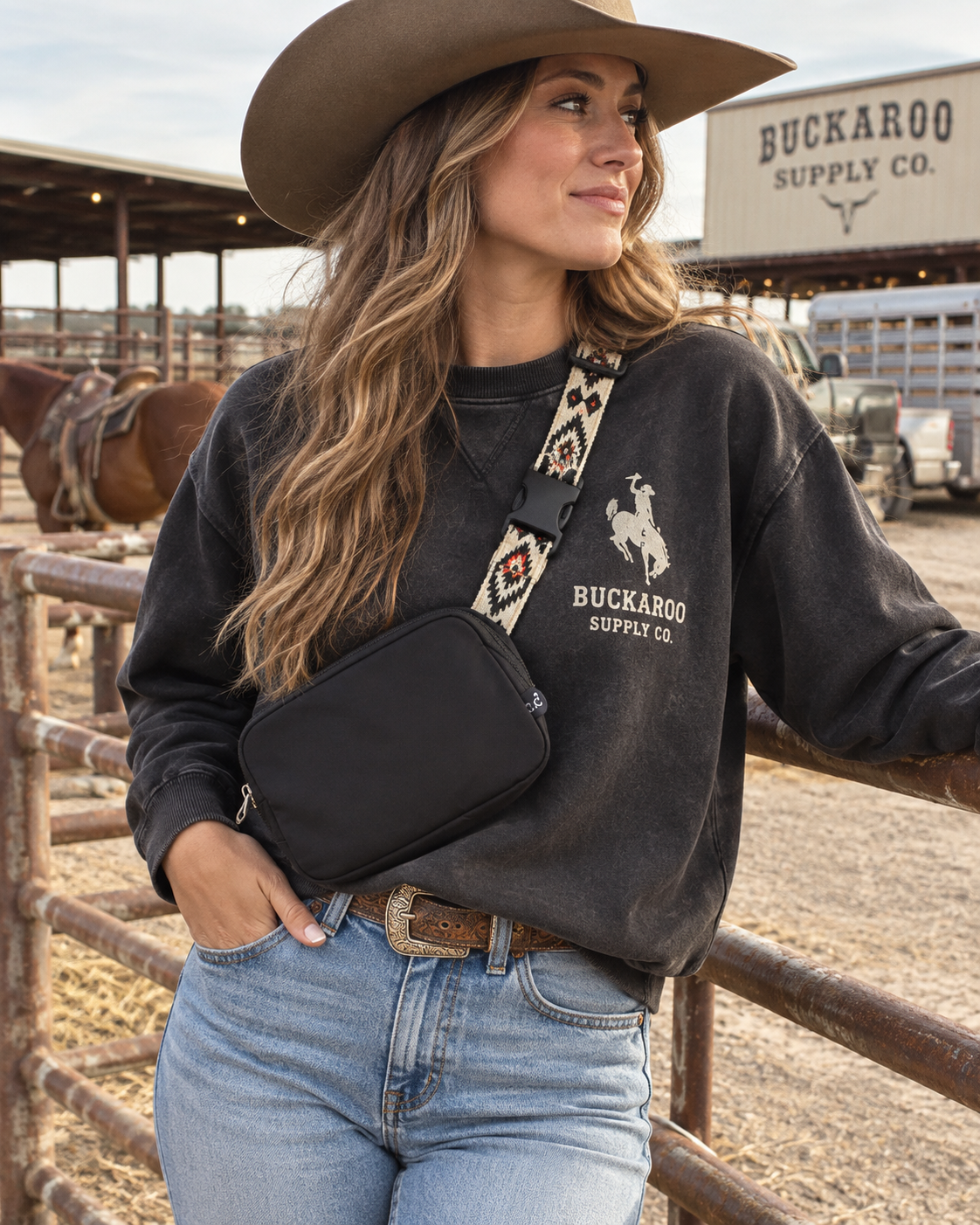 Cowgirl wearing black Western belt bag with Southwestern geometric strap at a rodeo ranch