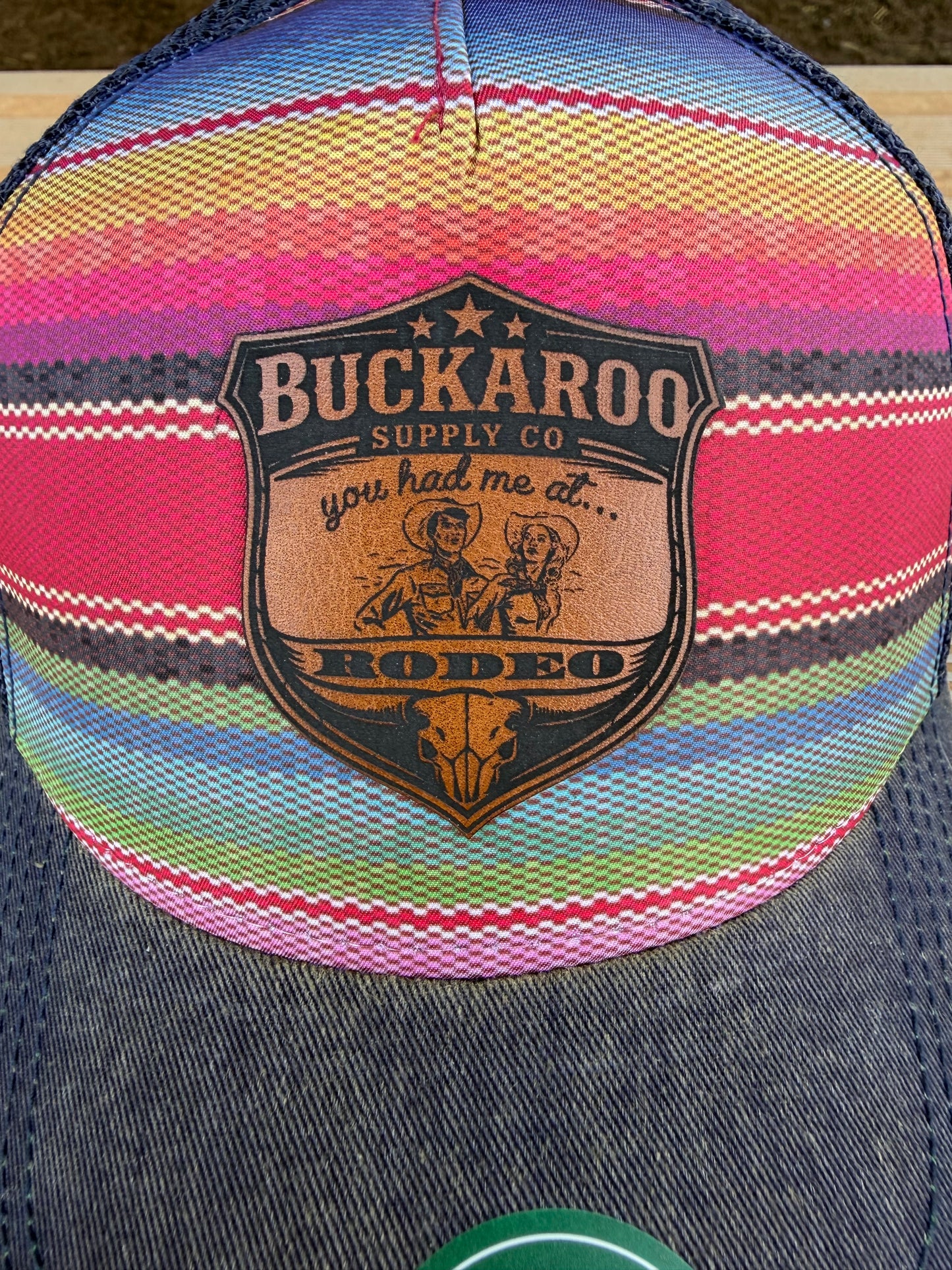 Colorful striped cap with Buckaroo Supply Co logo on a wooden surface