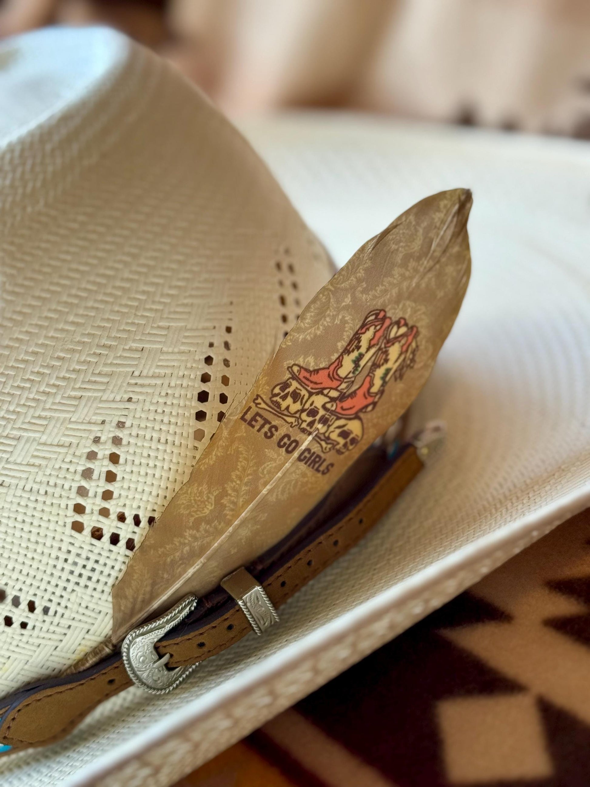 Cowboy hat feather with a decorative text "Let's Go Girls."