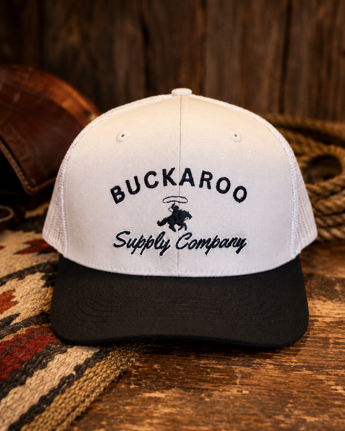 Tan and black Buckaroo Western trucker hat on rustic wood background