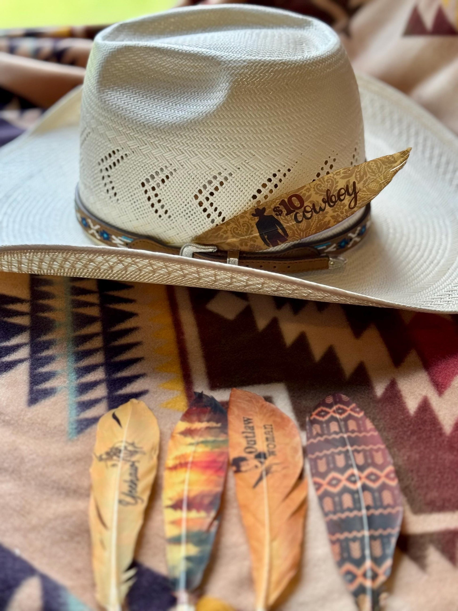 Cowboy hat with decorative band and feathers on a patterned surface