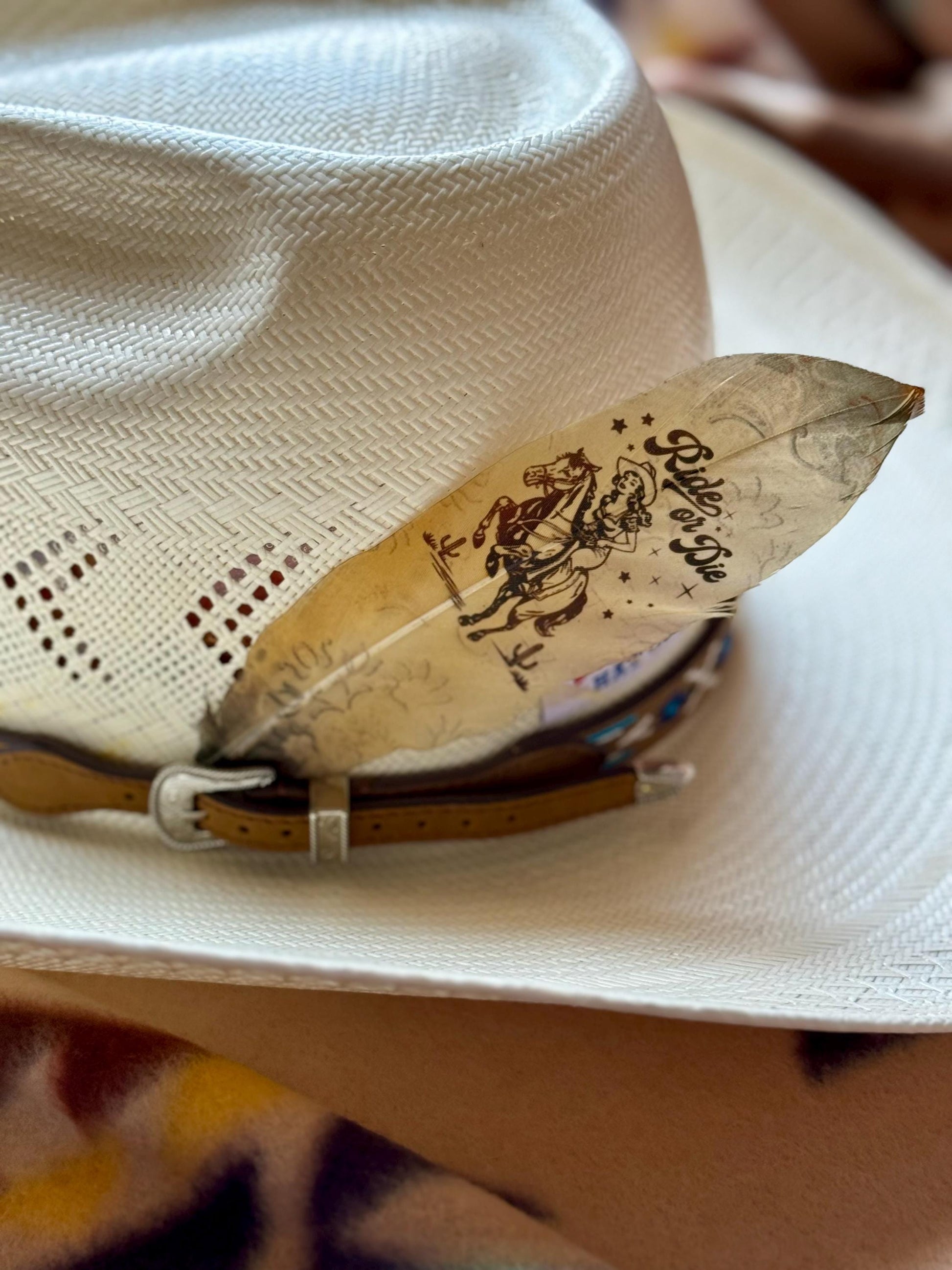 White cowboy hat with a decorative hat feather on a blurred background