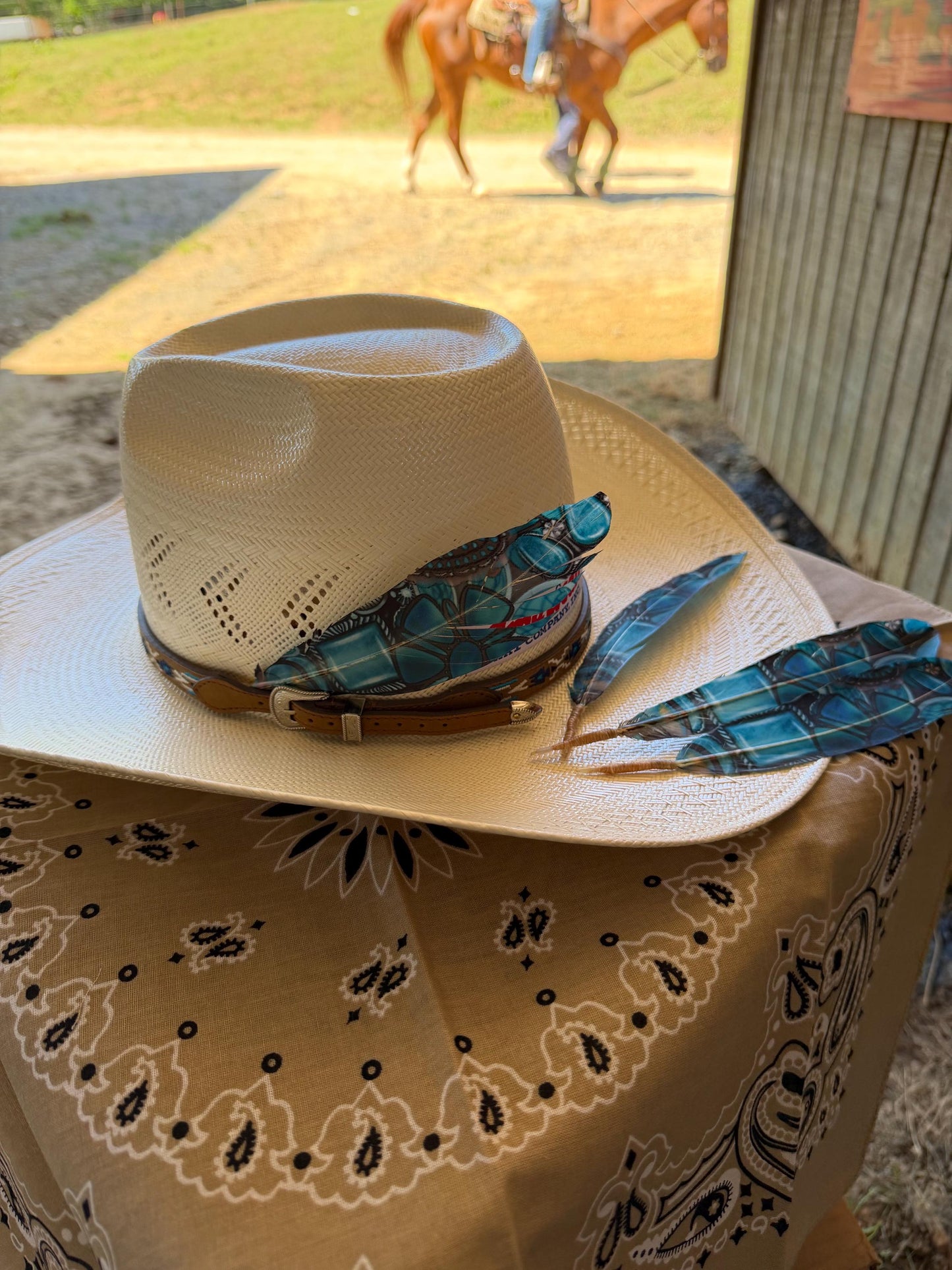 Blue turquoise Western hat feather displayed on a straw cowboy hat