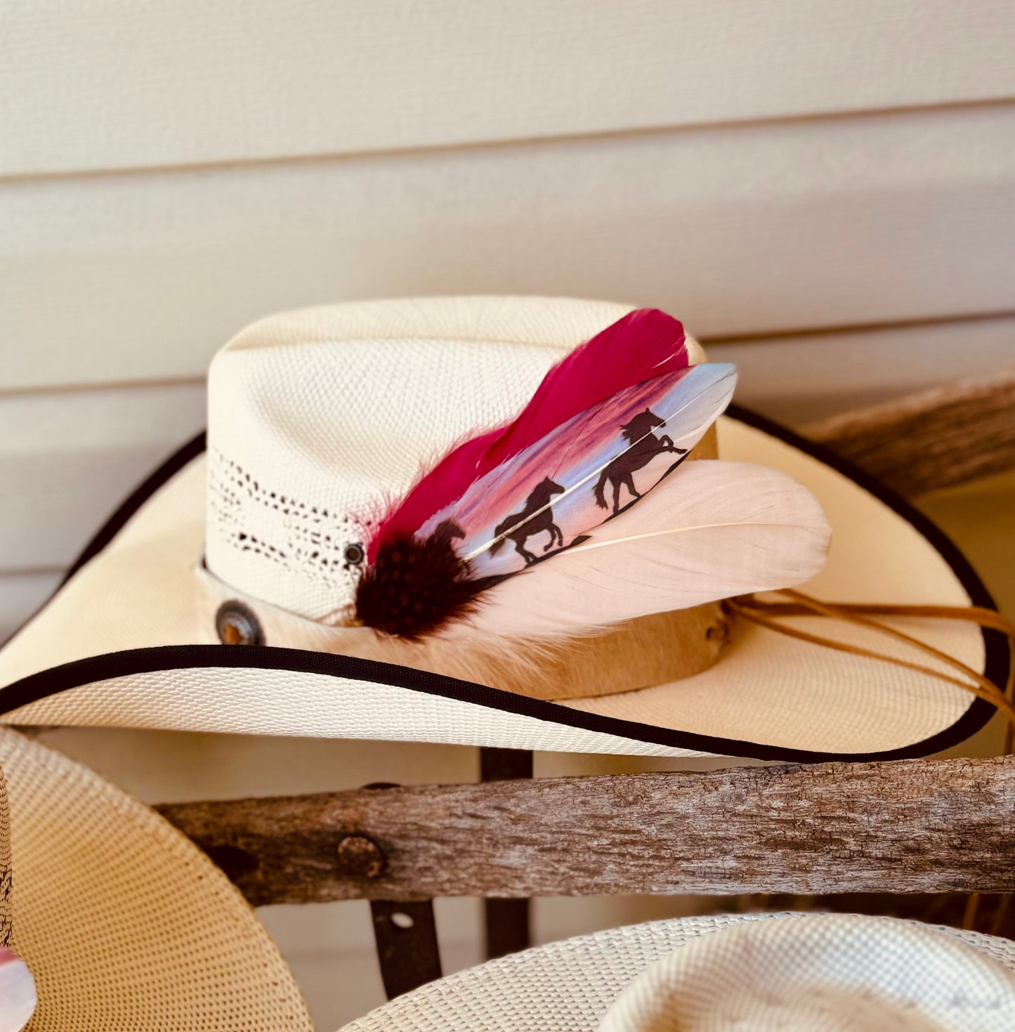 Beige straw hat with a decorative feather on a wooden surface