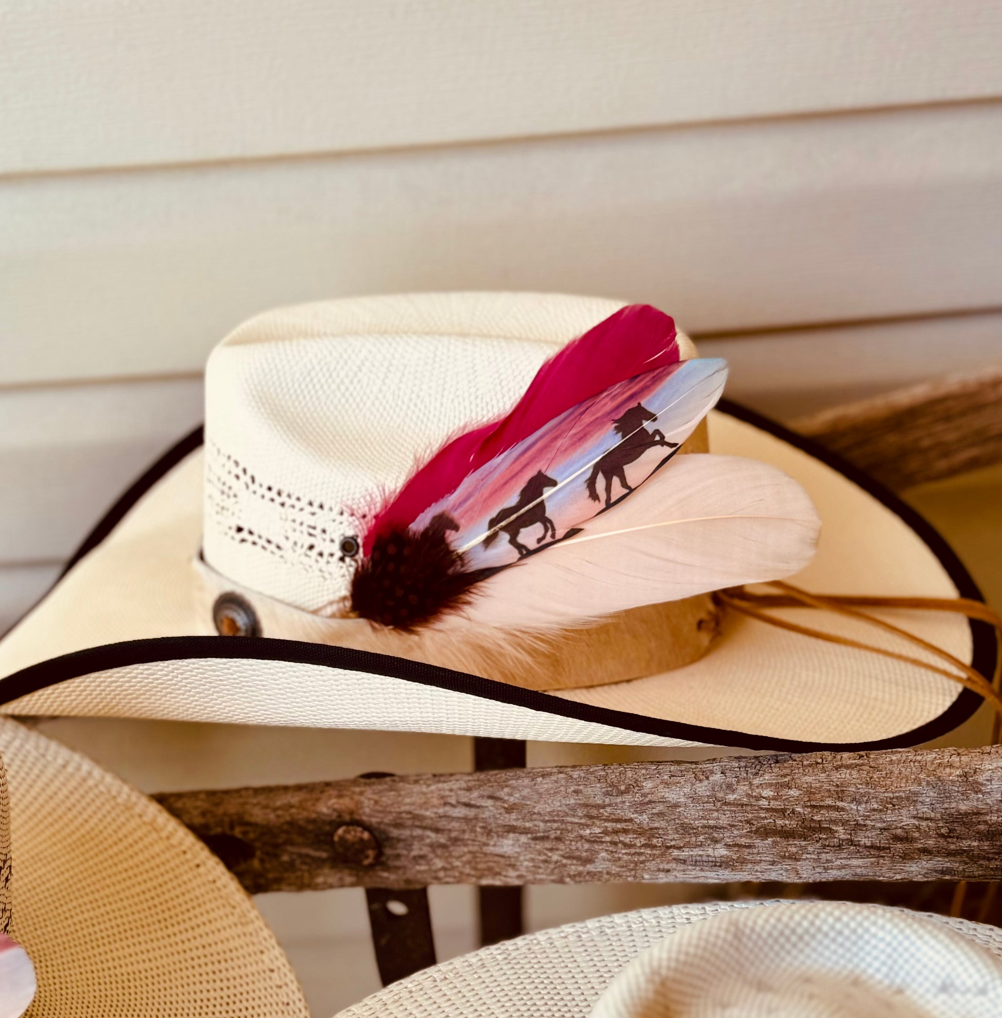 Beige straw hat with a decorative feather on a wooden surface
