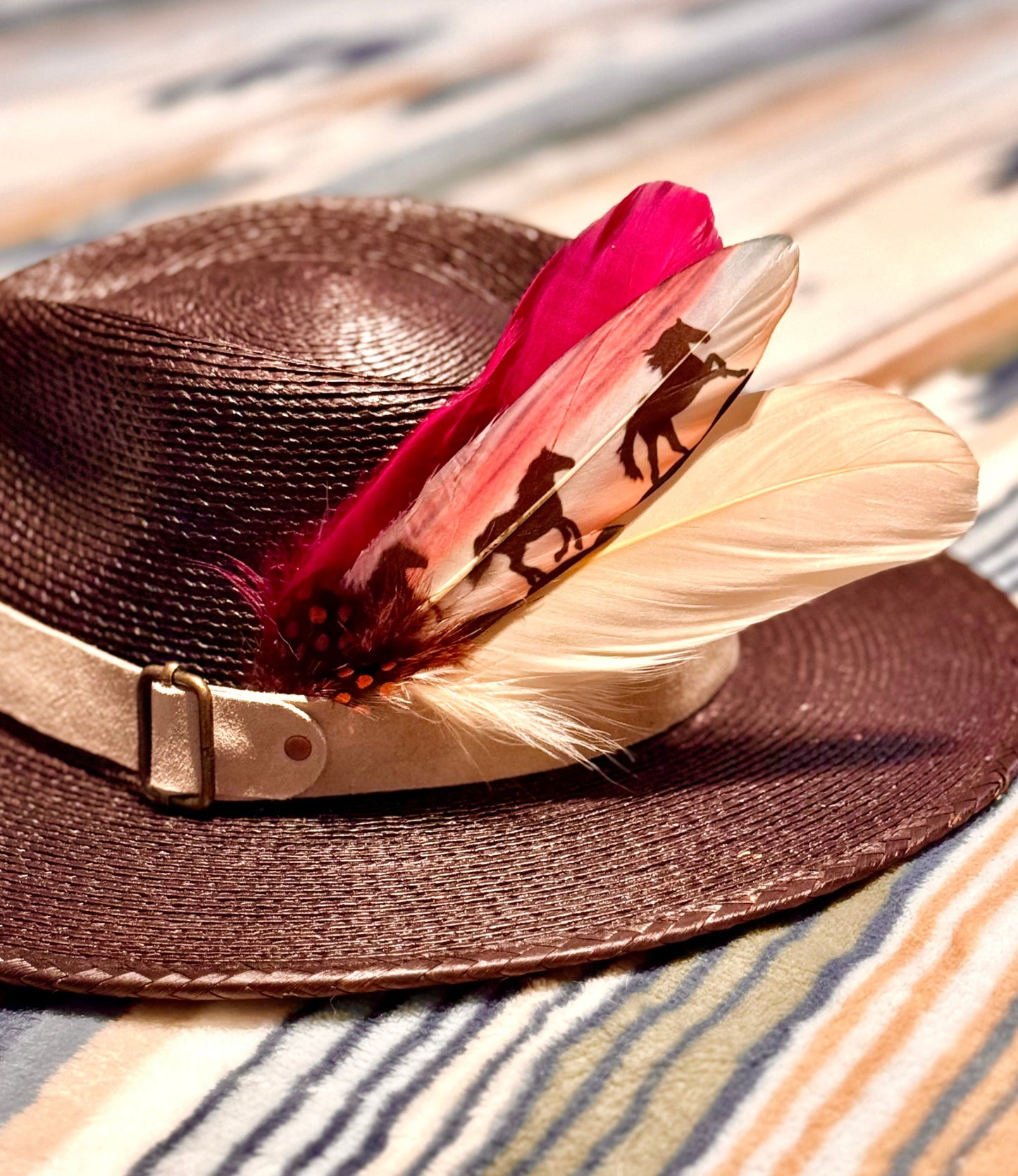 Brown straw hat with feathers on a striped fabric background