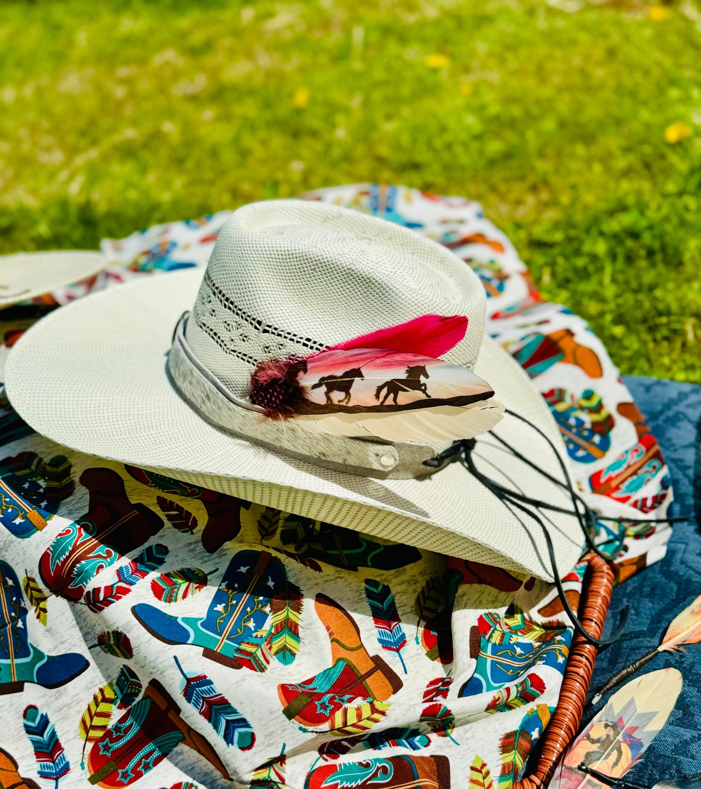 Cowboy hat with feather on a colorful patterned blanket outdoors
