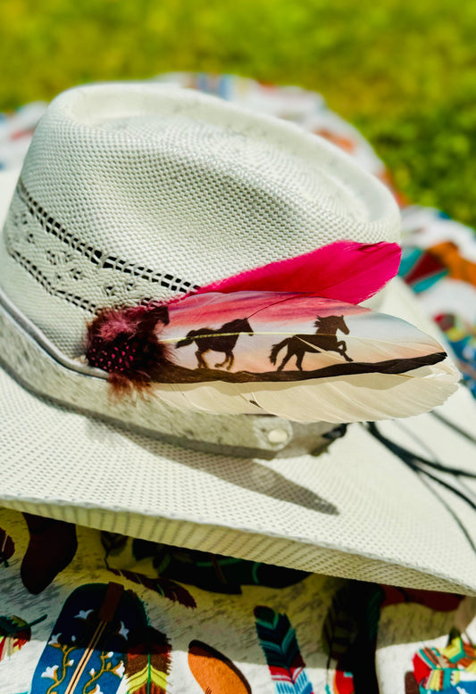 White cowboy hat with feather and horse design on a colorful fabric background